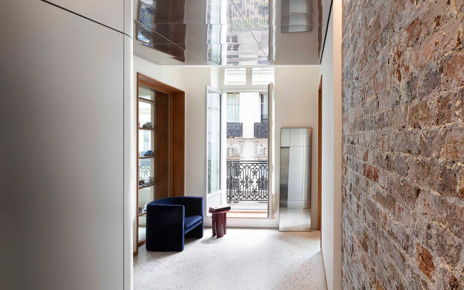 Modern interior designed with concrete and brick walls, featuring a sleek, black sofa and a glass door leading to a balcony.