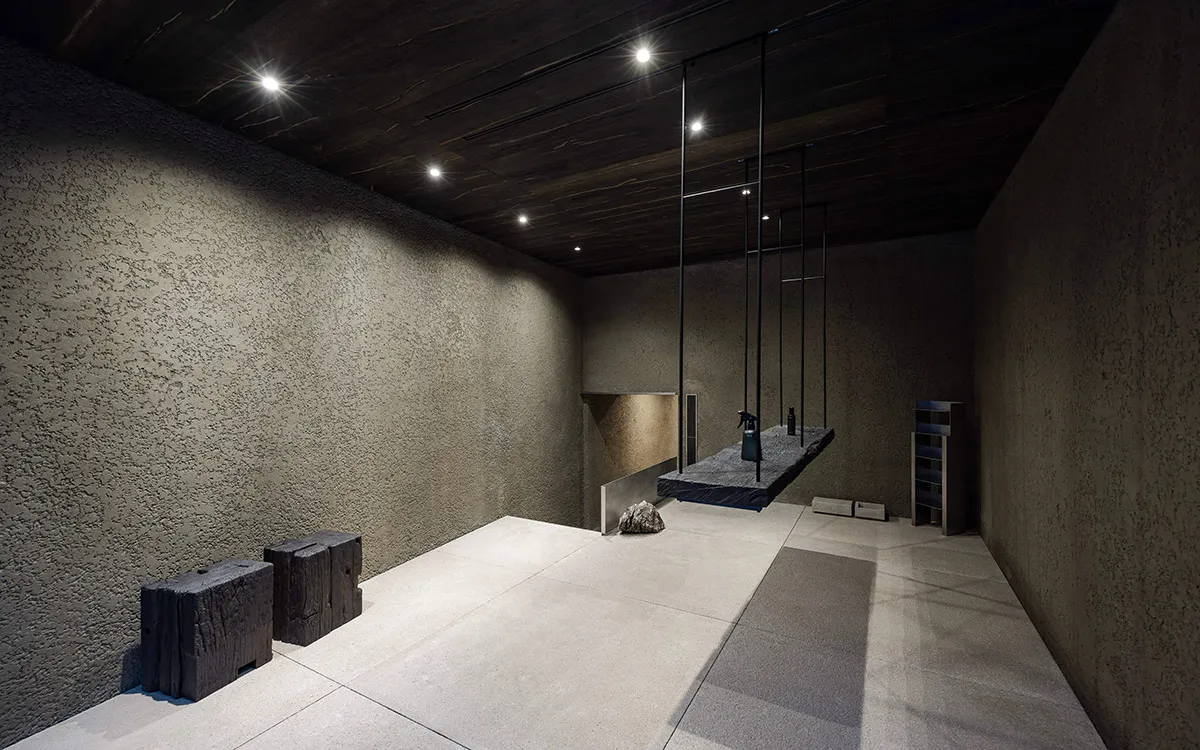 Minimalist art installation featuring concrete and metal elements hanging from the ceiling.