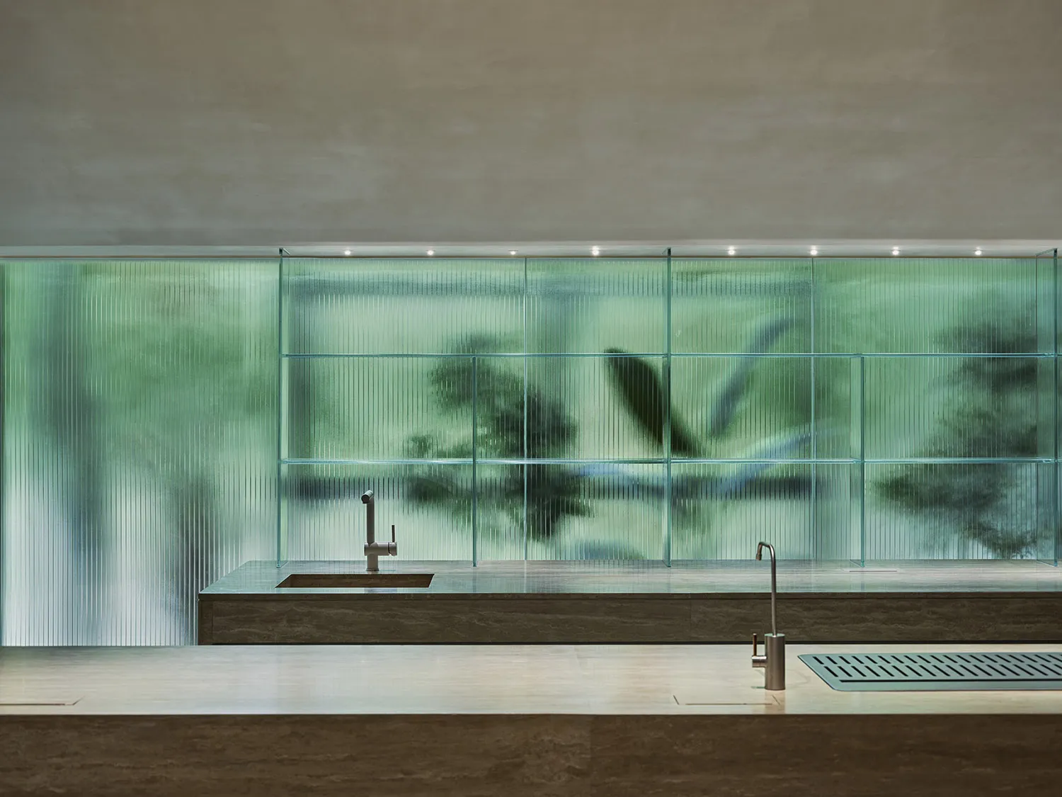 Modern kitchen featuring a marble countertop and a glass dividing wall.