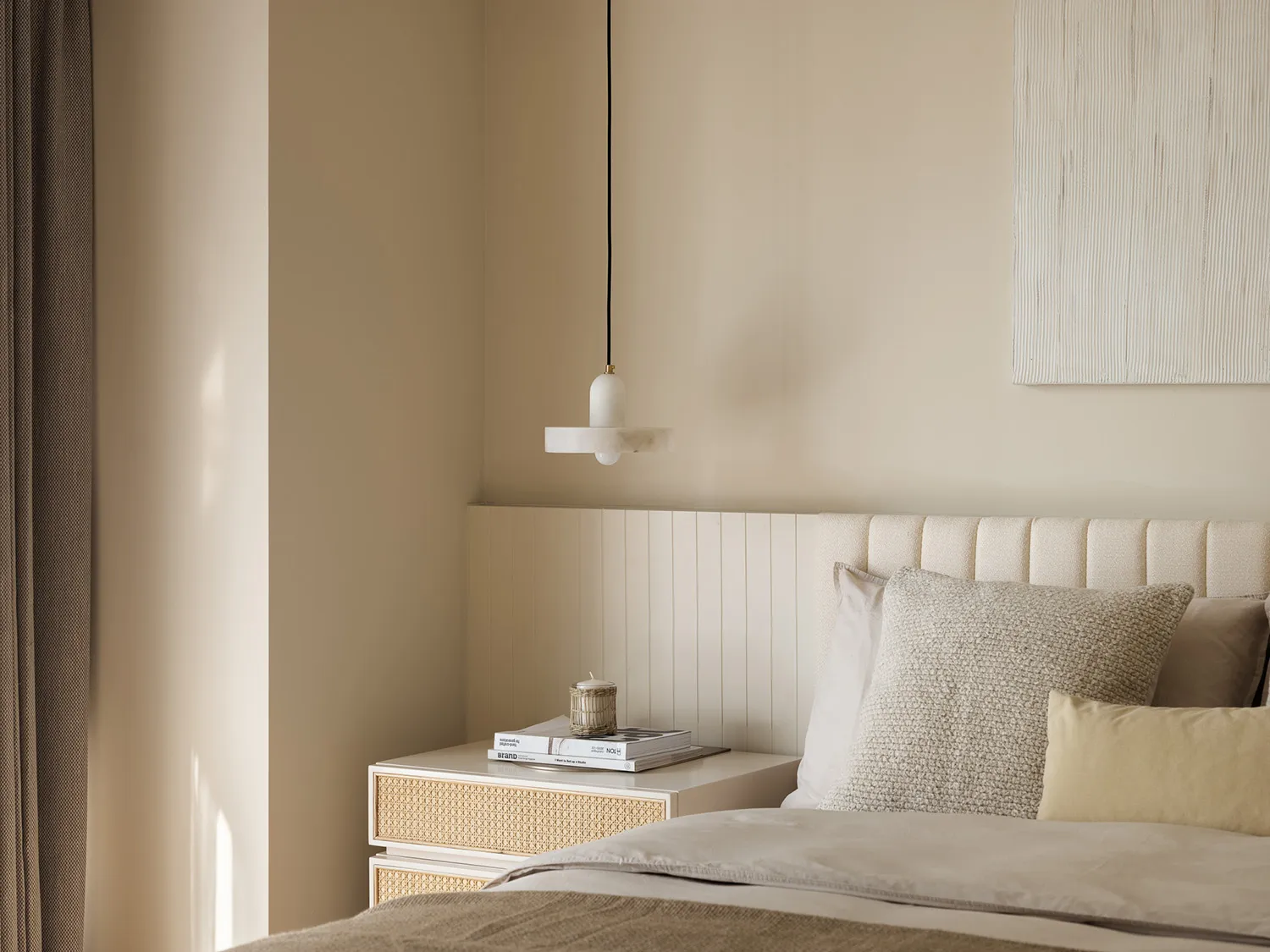 Contemporary minimalist bedroom interior with soft neutral tones, featuring a neatly made bed with white and grey pillows, a