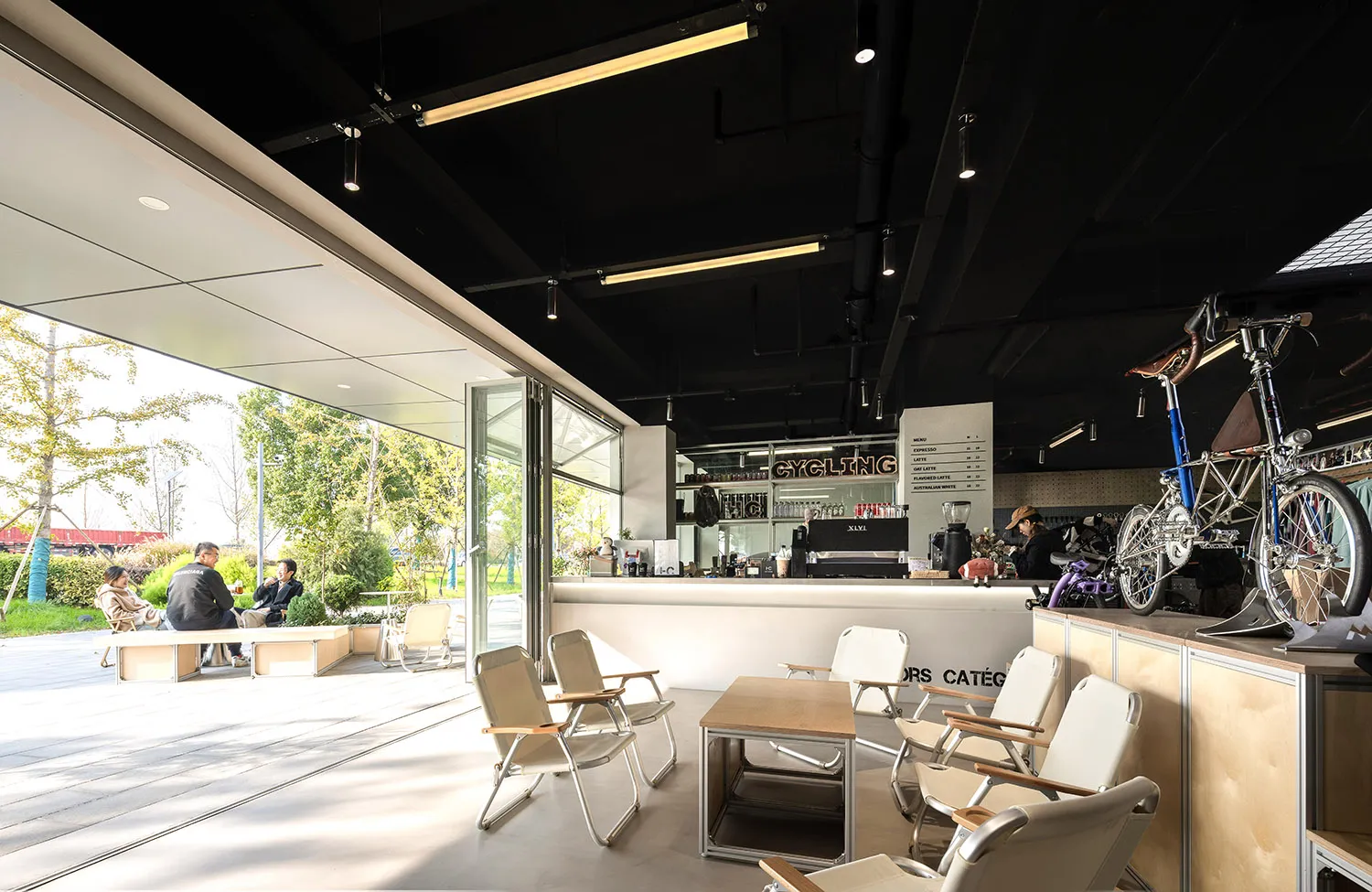 A modern, industrial-style coffee shop interior featuring metal-framed furniture, a concrete counter, and a relaxed seating a