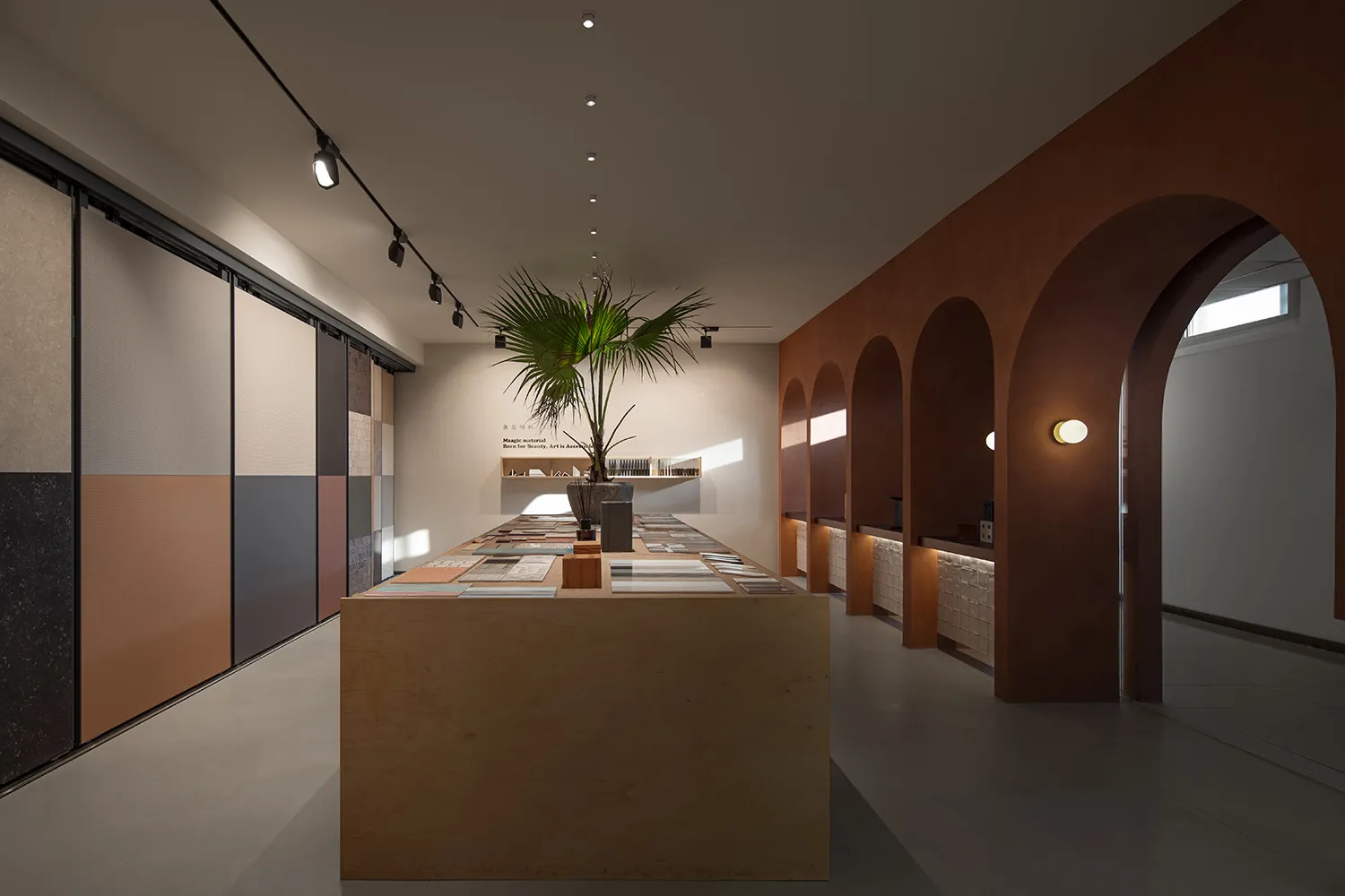A modern interior design showroom featuring a long display table showcasing various tiles.