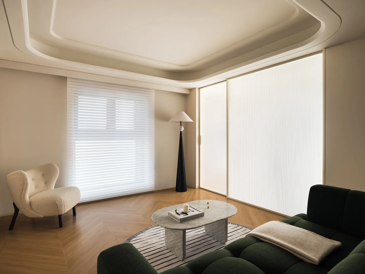 A minimalist modern living room with a green sofa, marble coffee table, and a floor lamp with white lampshade.