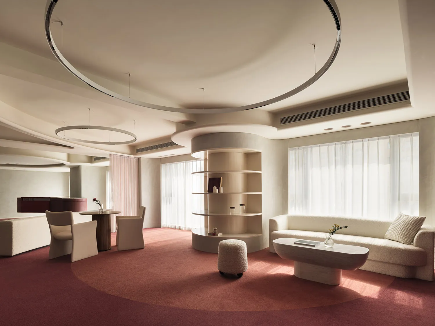 Modern minimalist living room with fabric seating, plaster walls, glass shelves, and wooden furniture.