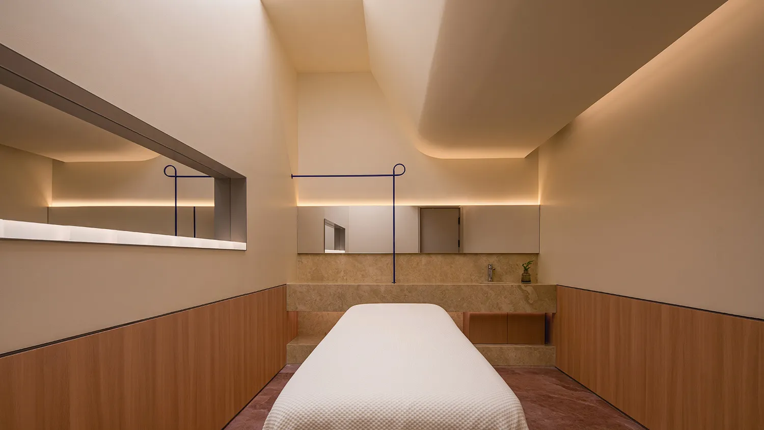 A minimalist spa room with stone walls and a white bed.
