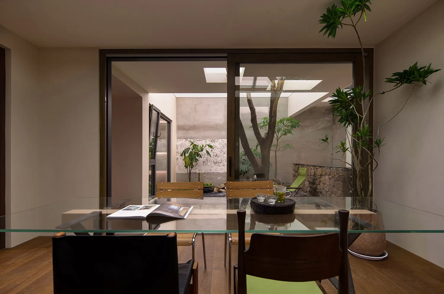 Modern dining room featuring glass furniture and a glass table with plants and drinks.