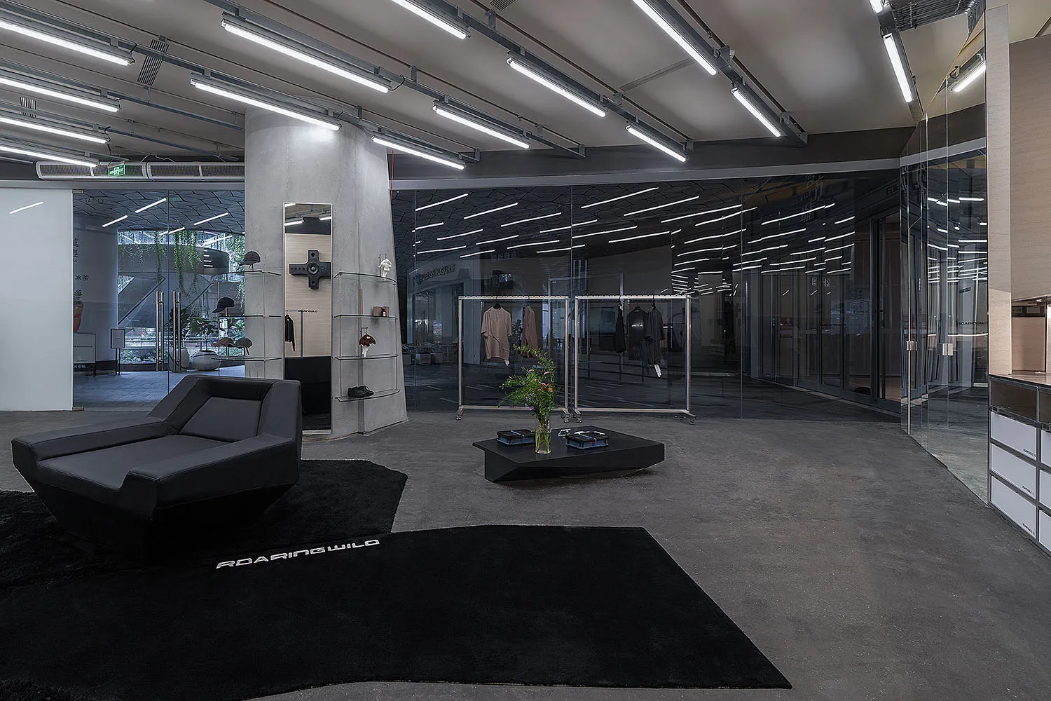 Interior of a modern retail clothing store with industrial design elements, including concrete walls, glass display cases, an