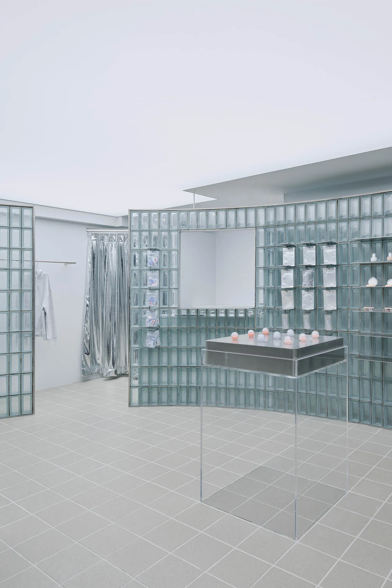 A modern bathroom featuring glass block walls and a clear acrylic pedestal with spherical objects.