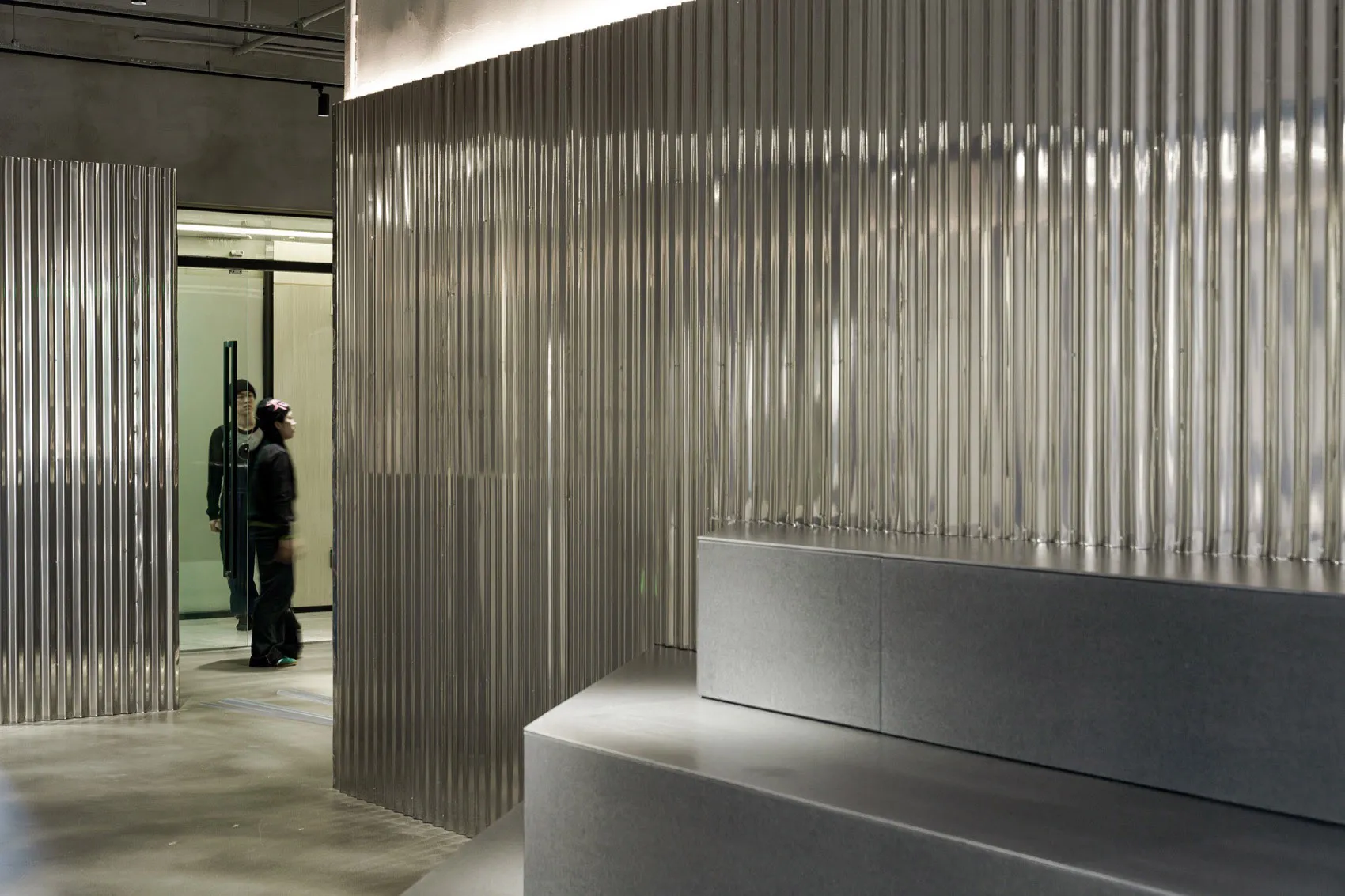 A modern office reception area featuring metallic walls and minimalist design elements.