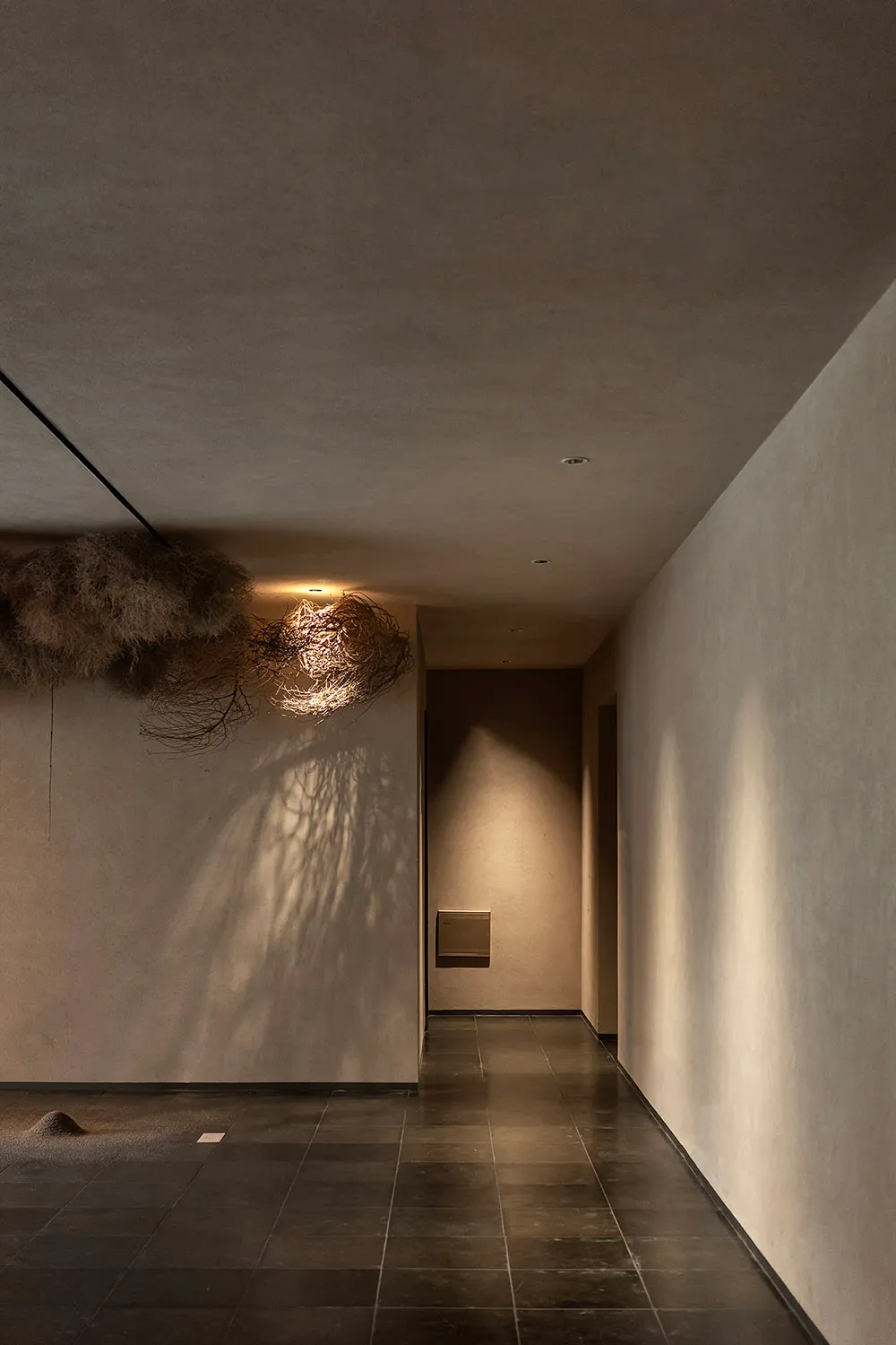 Fabric lighting fixture in a corridor with concrete walls and floor tiles.
