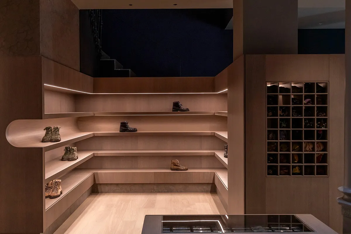 A modern retail space with organized wooden shelves displaying shoes and boots.
