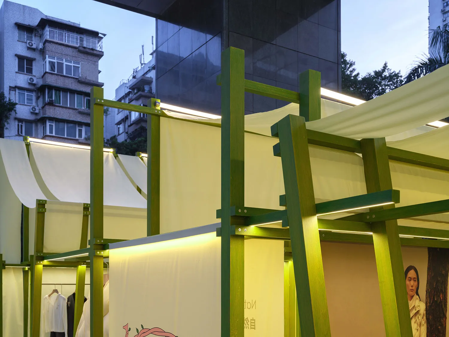 A modern shop interior with green wooden structures and white fabric elements.