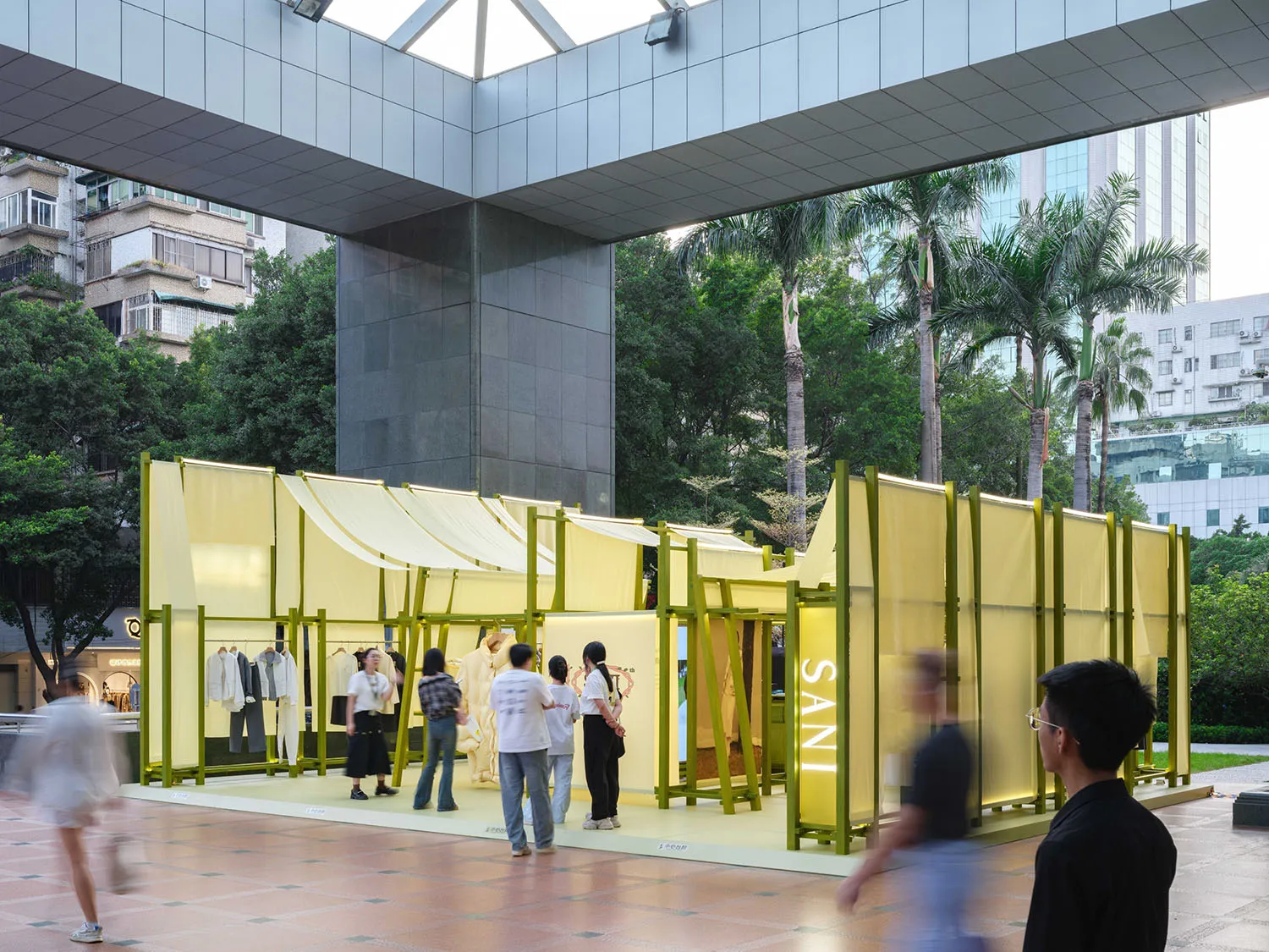 Pop-up store with yellow fabric walls and metal frames in an urban setting.