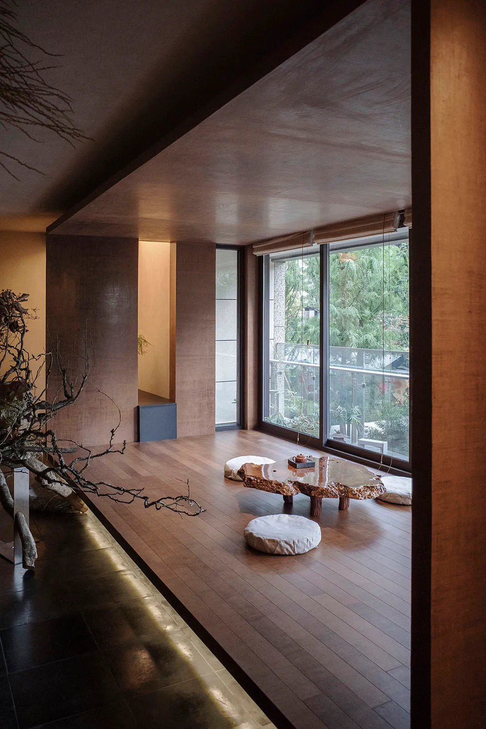 A modern living room with a wooden floor, a tree trunk table, and white cushions.
