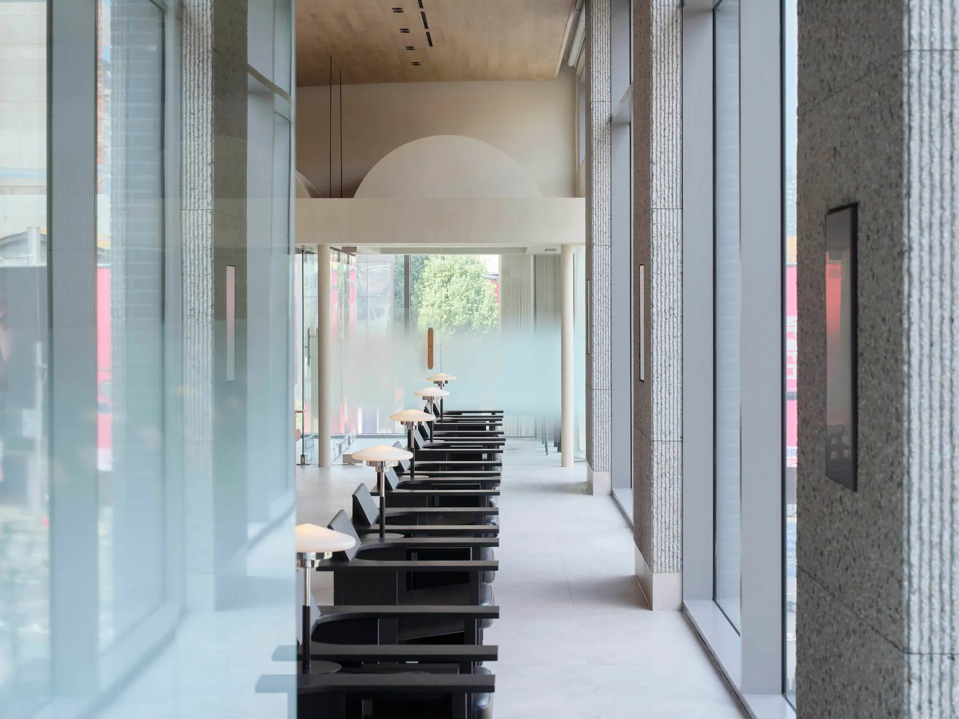 A modern restaurant interior featuring glass walls and concrete flooring.