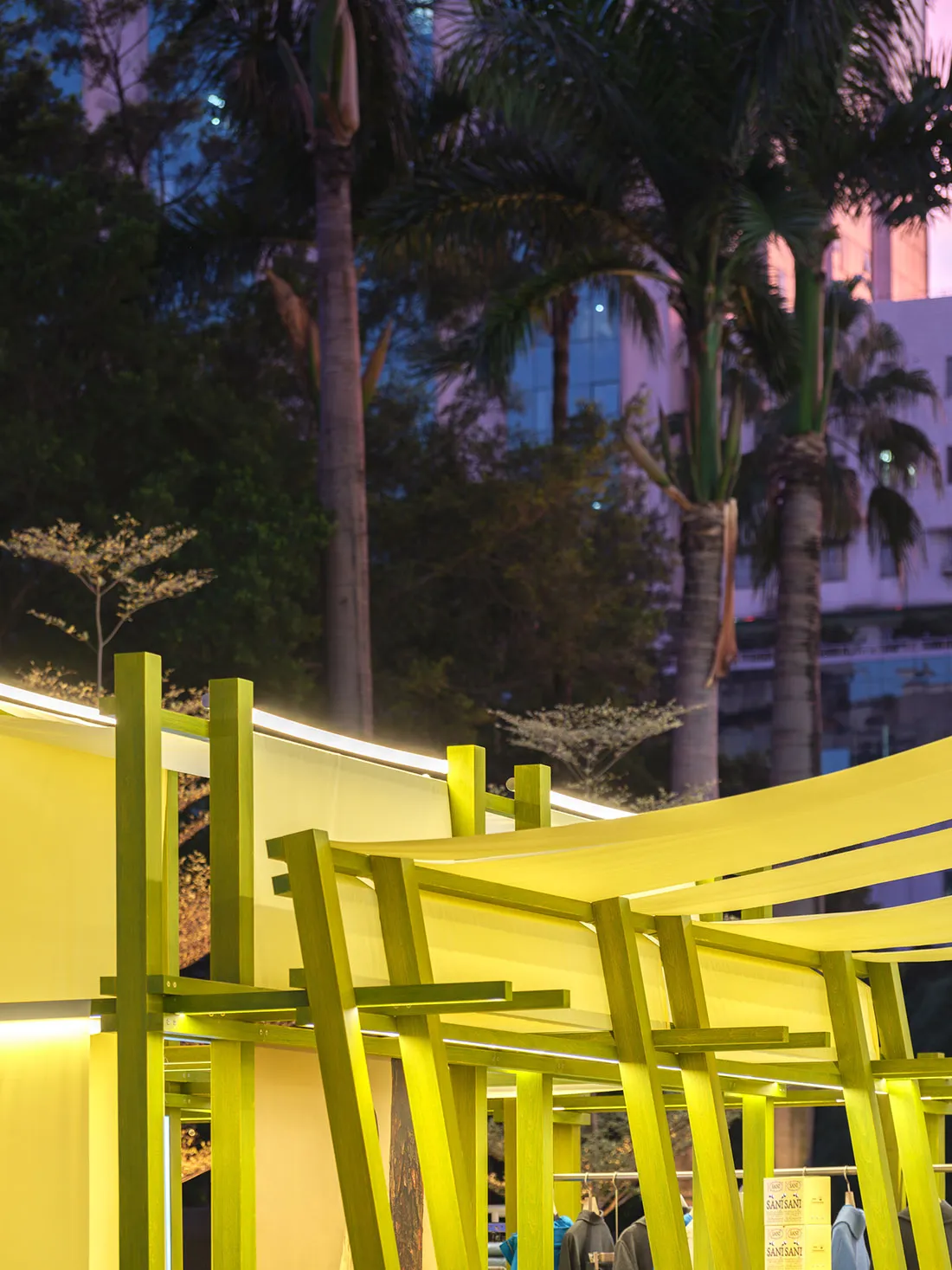 Modern storefront featuring bright yellow fabric and wooden beams.