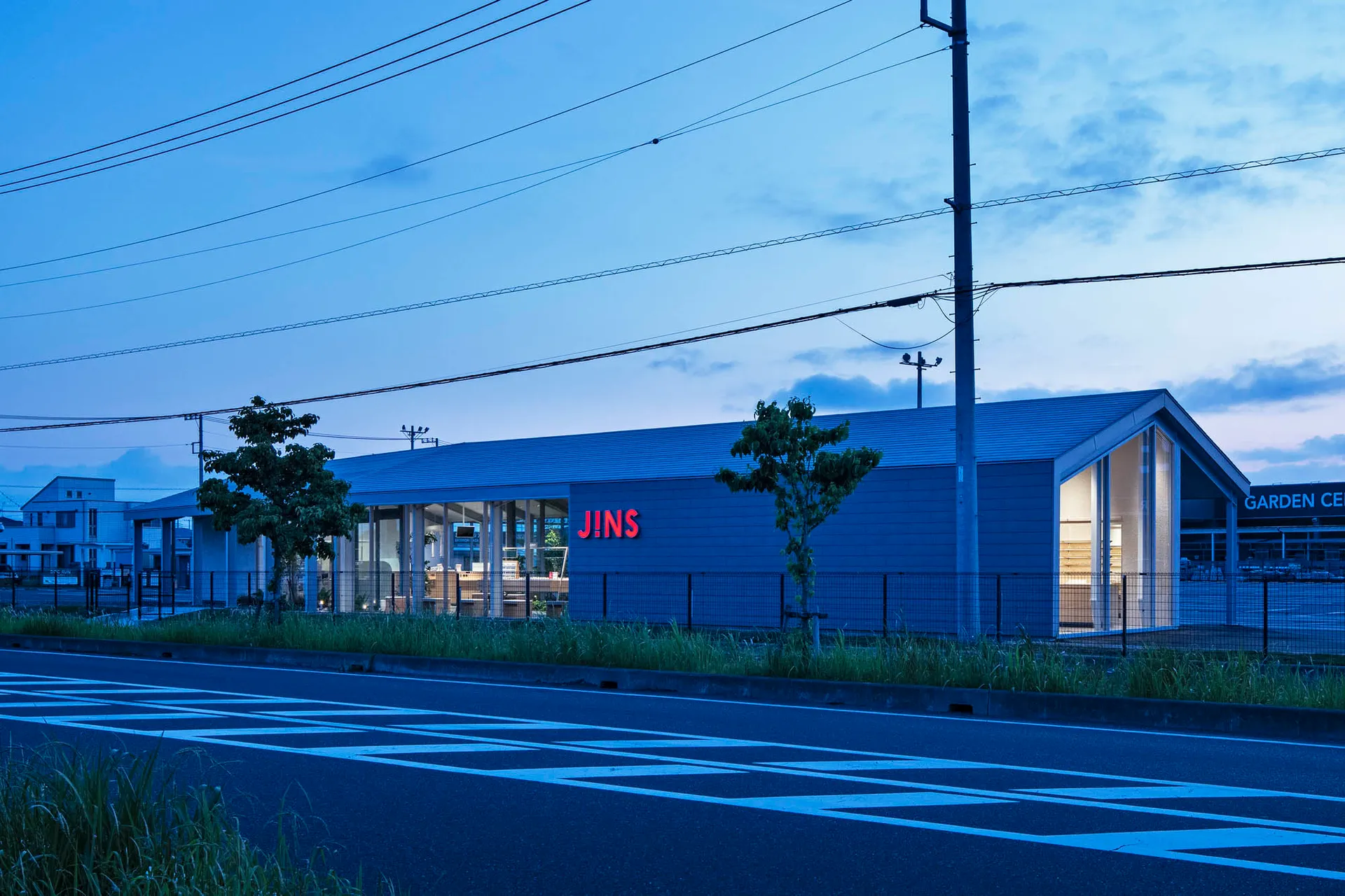 Modern storefront with blue metal cladding, featuring large glass windows and a prominent signage.