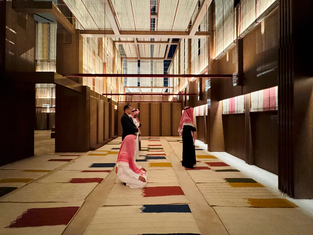 A modern hallway with colorful carpet tiles and a high ceiling with exposed beams.