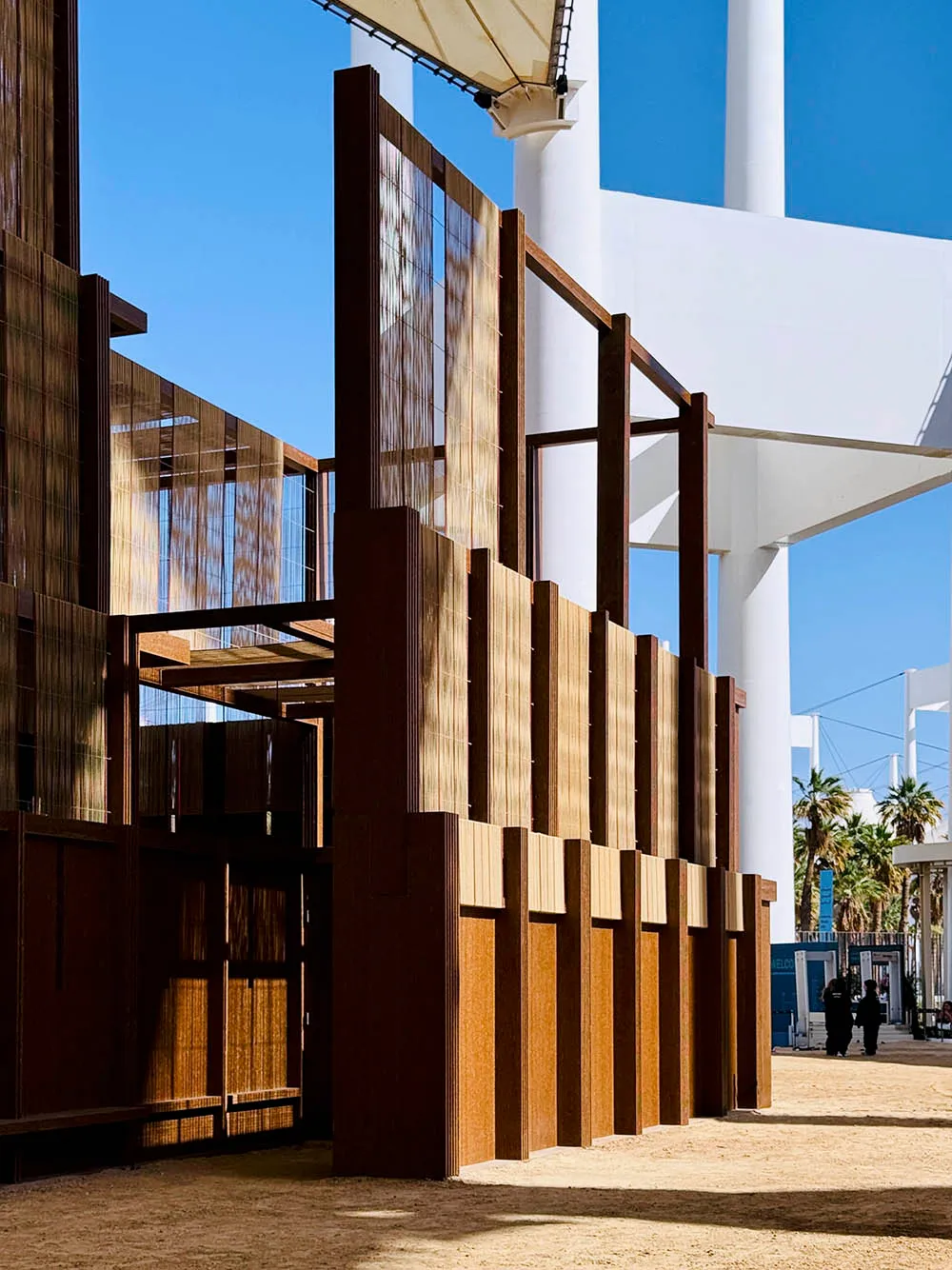 A modern metallic architectural exterior with vertical panels and a clear blue sky in the background.