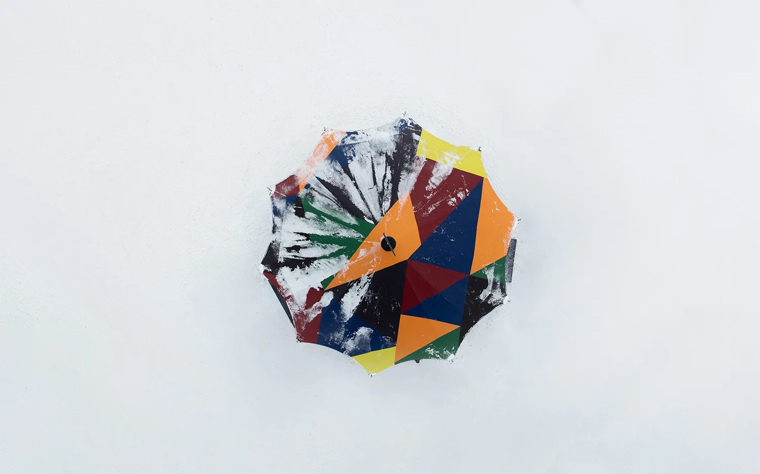 A colorful and abstract-patterned umbrella on a white surface