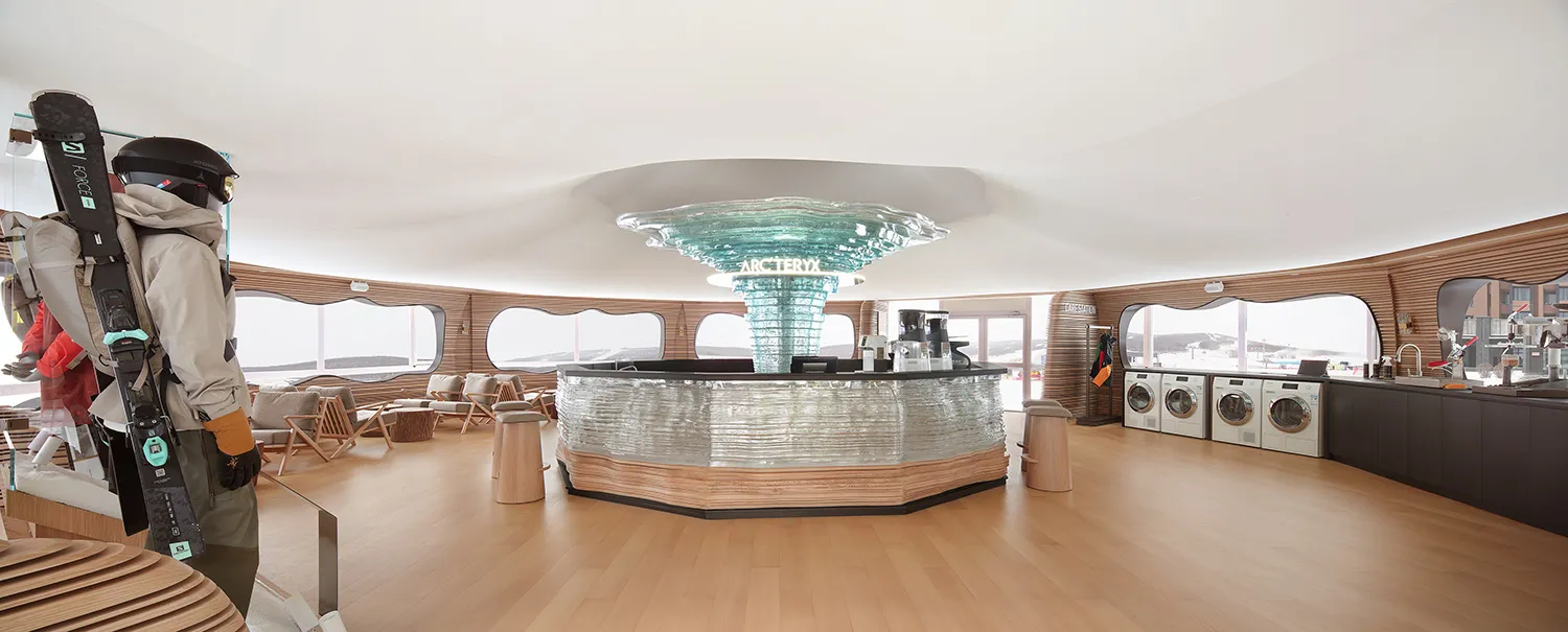 A spacious hotel interior featuring a central bar area with a glass dome ceiling, wooden flooring, and multiple seating optio