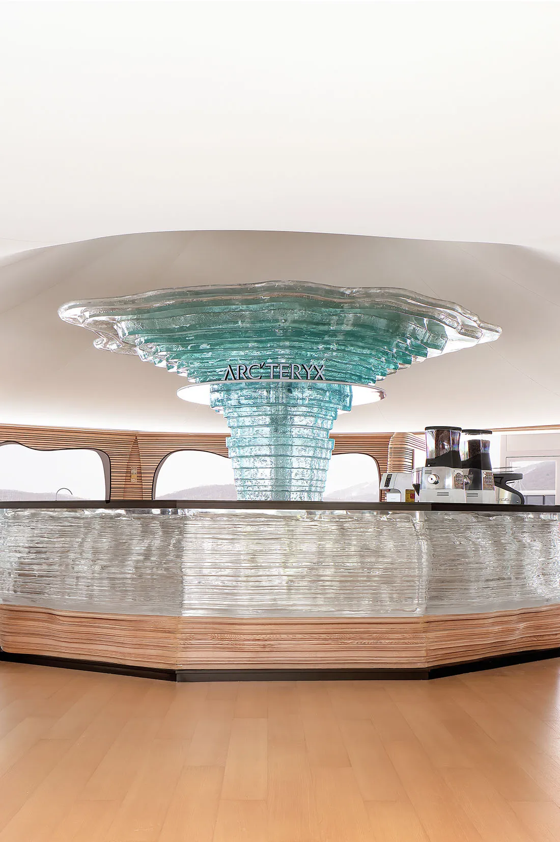 A modern coffee shop counter featuring a glass design with a glass top and stand.