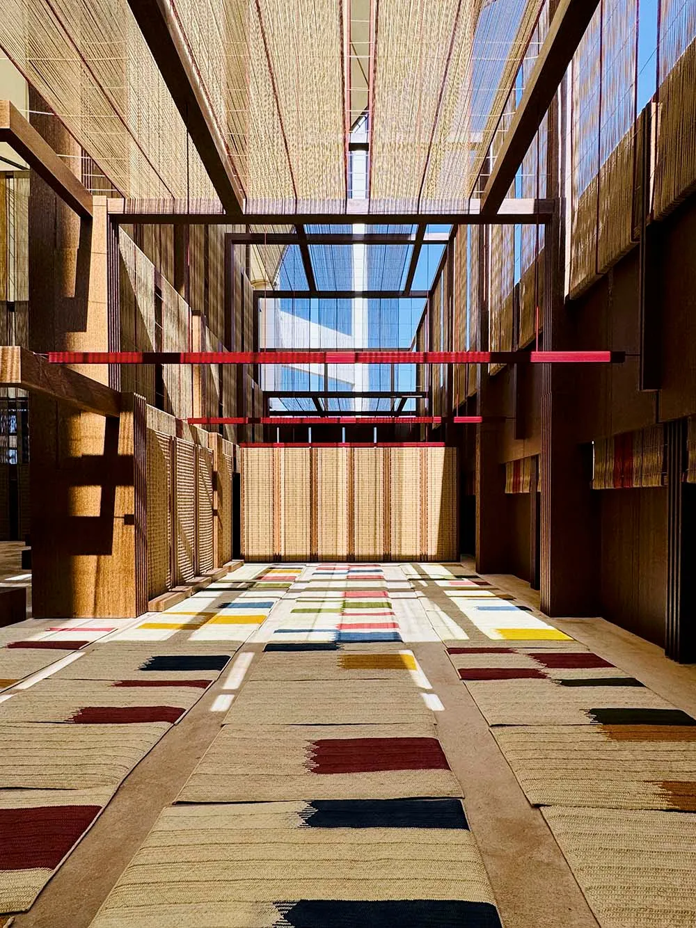 A modern corridor with colorful floor tiles, wooden walls, and concrete flooring under a skylight with natural light streamin