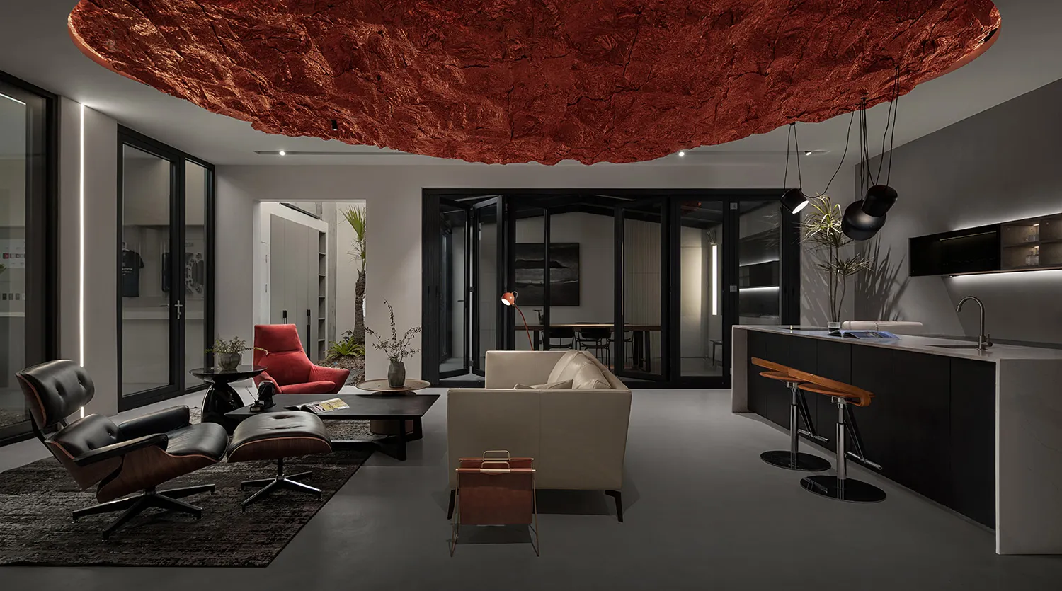 A modern living room with metallic accents and a large, floating red rock-like ceiling ornament.
