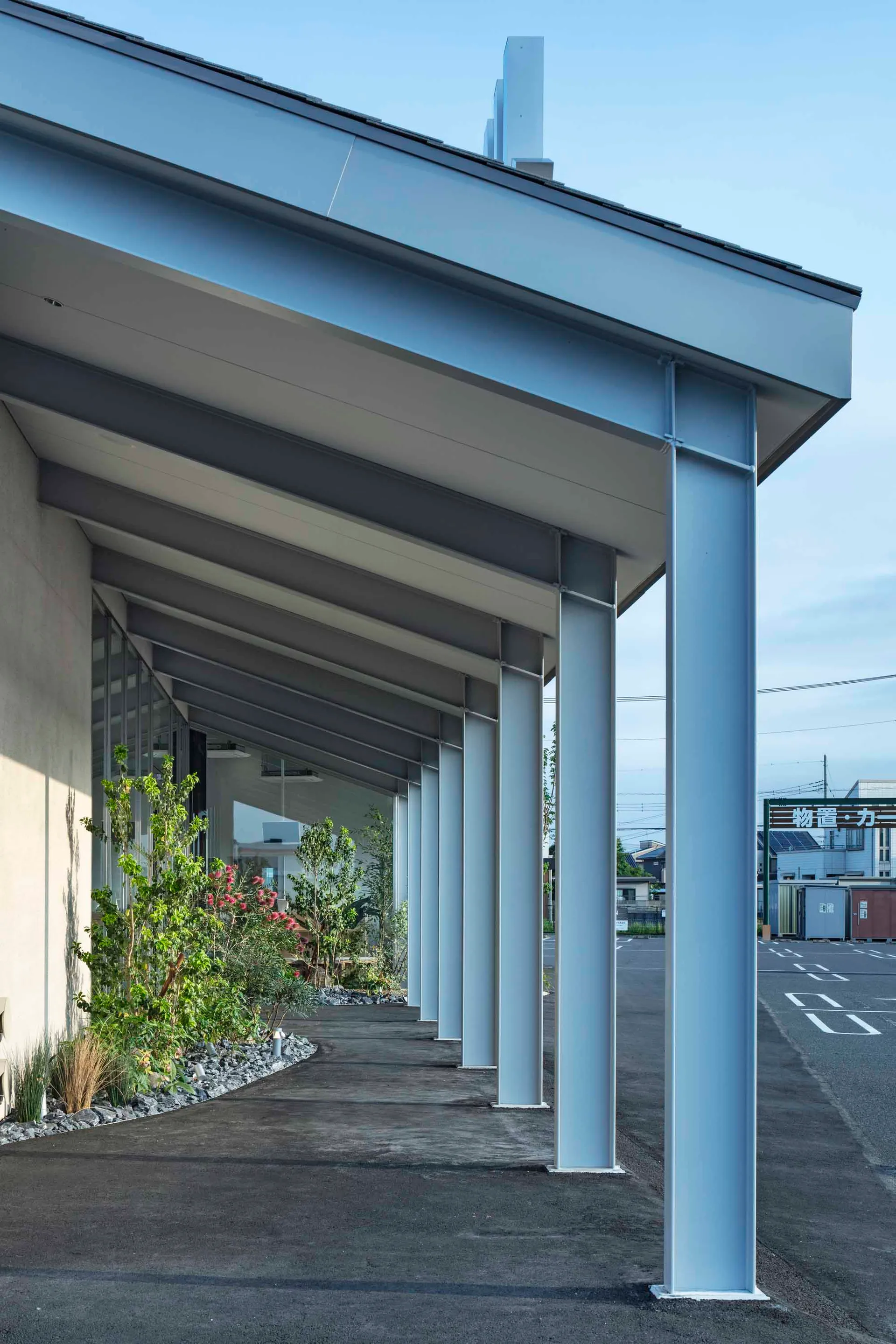 Modern building exterior with metal columns and a concrete overhang and roof