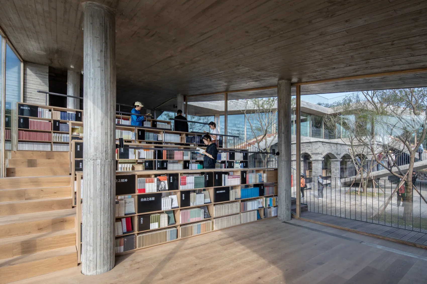 A modern library interior with concrete walls and floors, featuring bookshelves filled with books.