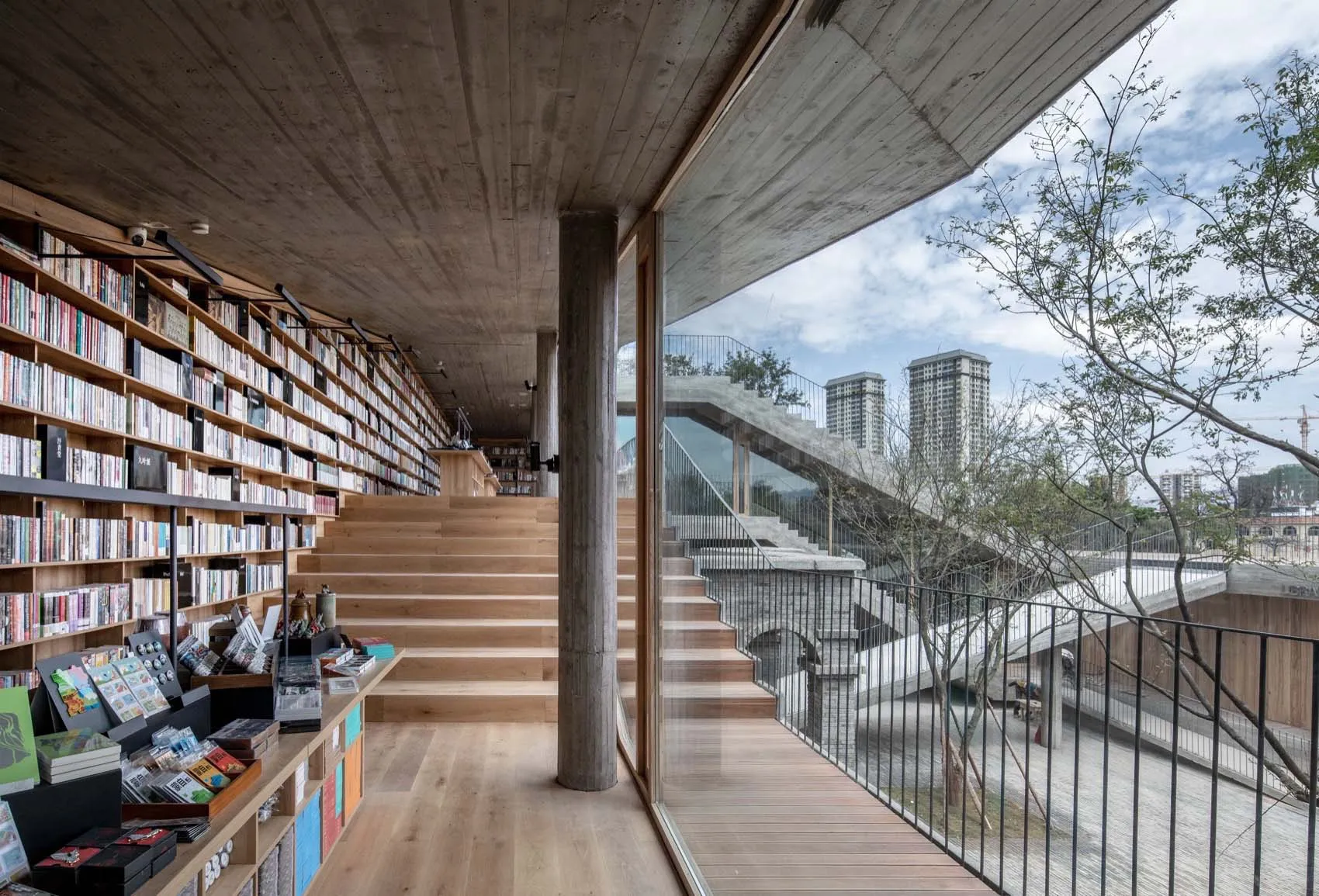 現代圖書館室內,木質書架、混凝土天花板,以及俯瞰城市景觀的玻璃牆。
