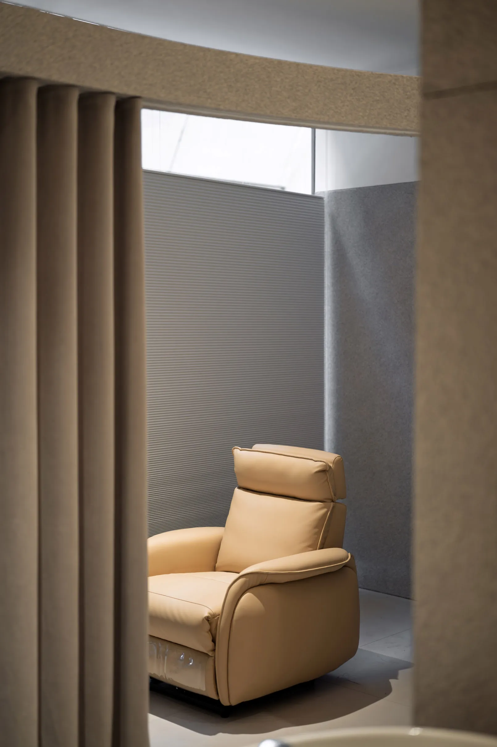 Modern living room featuring a beige leather recliner chair, with a bluish-grey textured wall and a frosted glass partition.