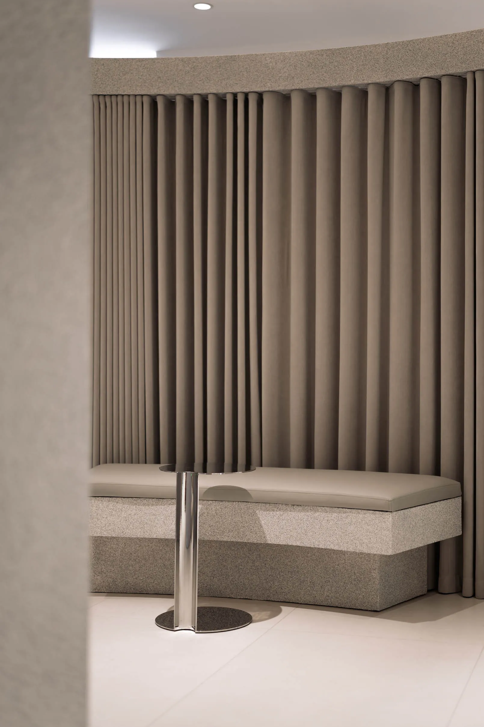 Modern waiting room with fabric seating, marble base, and metal table.