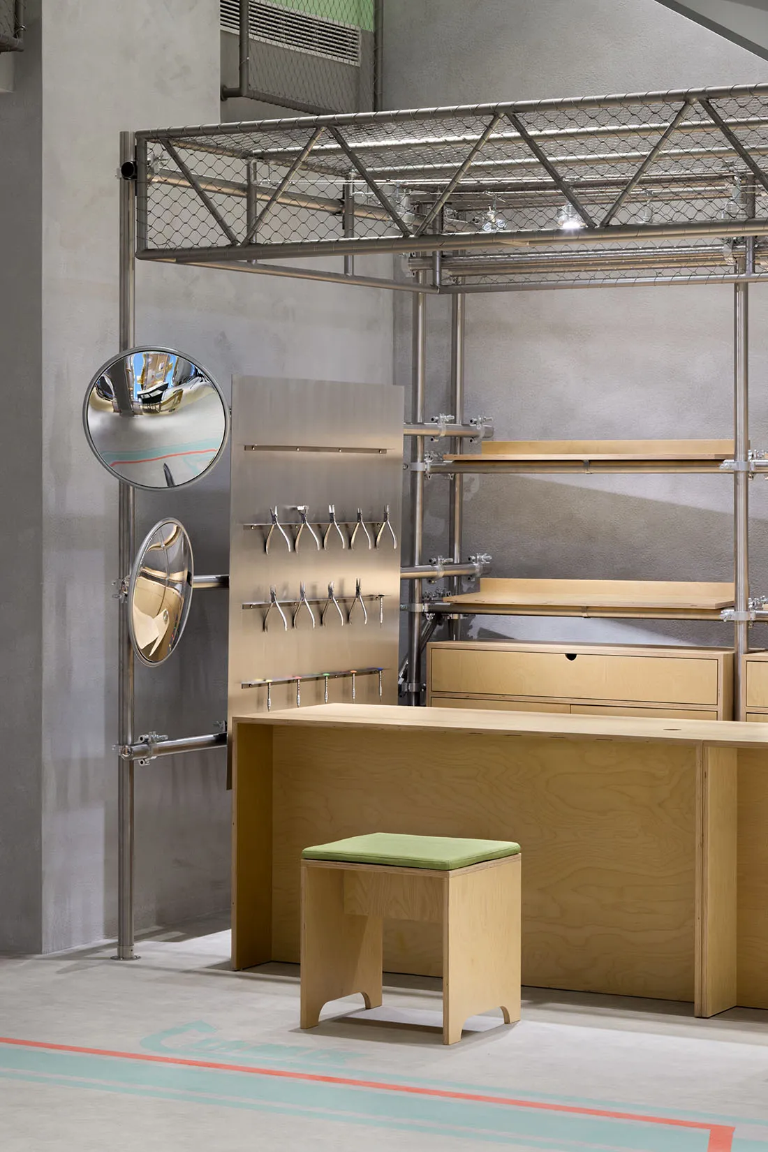 Industrial-style workshop with metal scaffolding, wooden tables, and concrete floor.