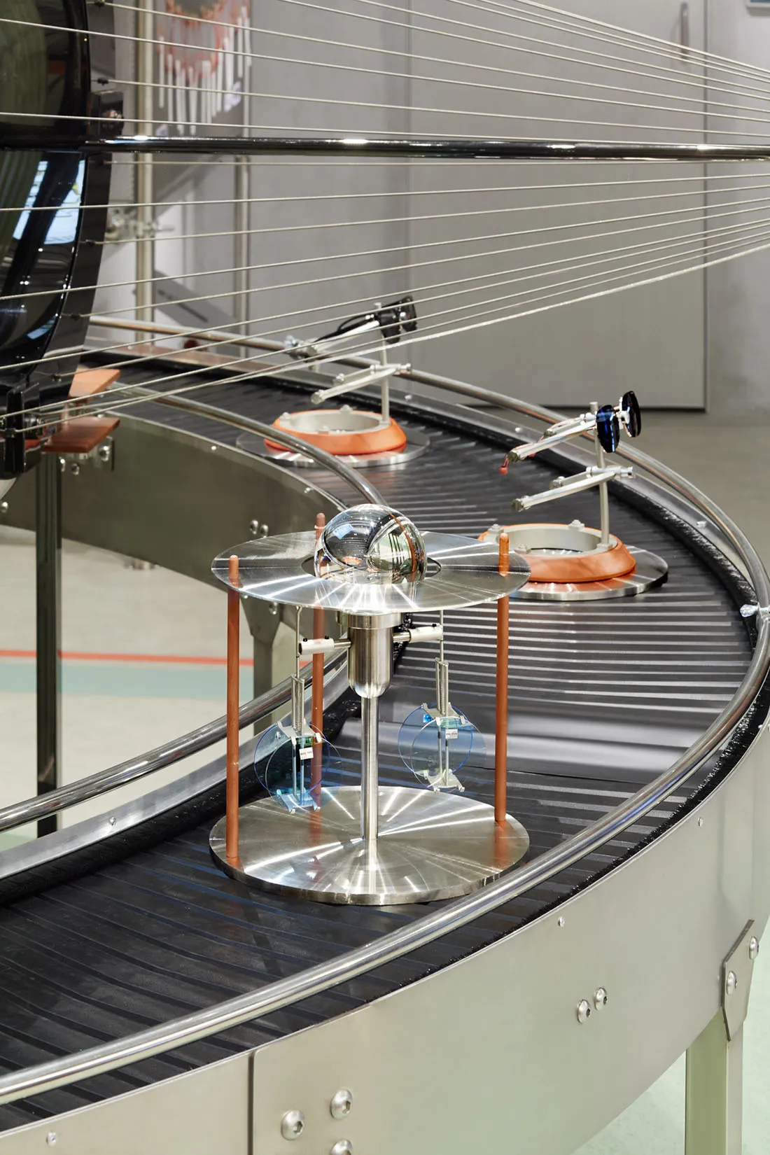 A metallic industrial machine with a globe and various components on a conveyor belt.