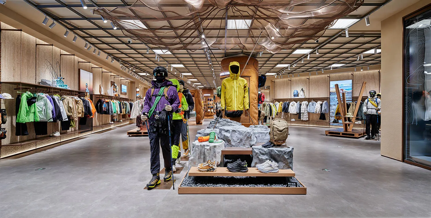 一間展示運動服飾與配件之零售店，展示模特兒穿著戶外裝備，貨架上擺滿服裝