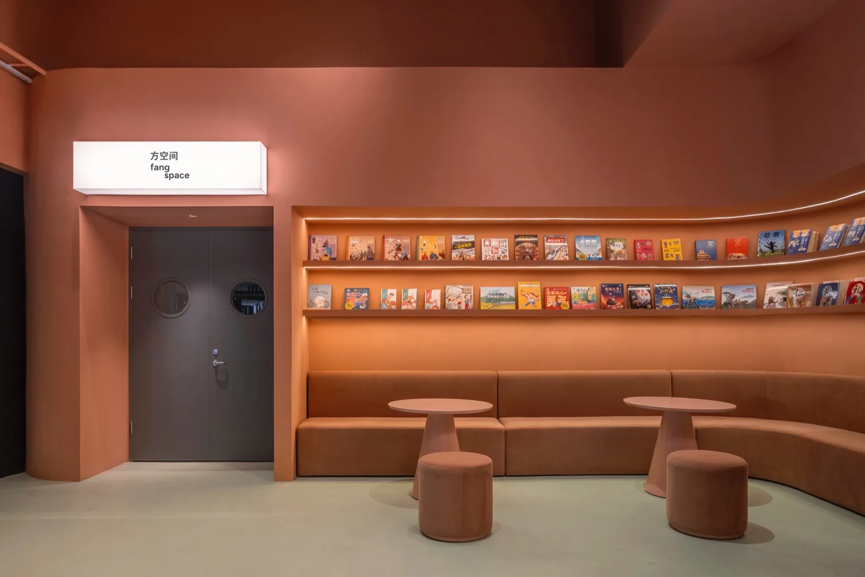 舒適的圖書空間,配有棕色皮革座椅、擺滿各式書籍的書架,以及兩張附有圓凳的小圓桌
