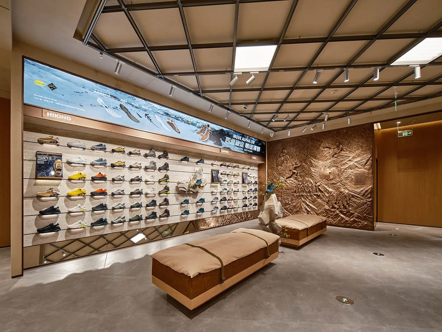 一間鞋店零售空間，牆面展示各式鞋款，搭配木製長椅與大型螢幕播放鞋款系列。