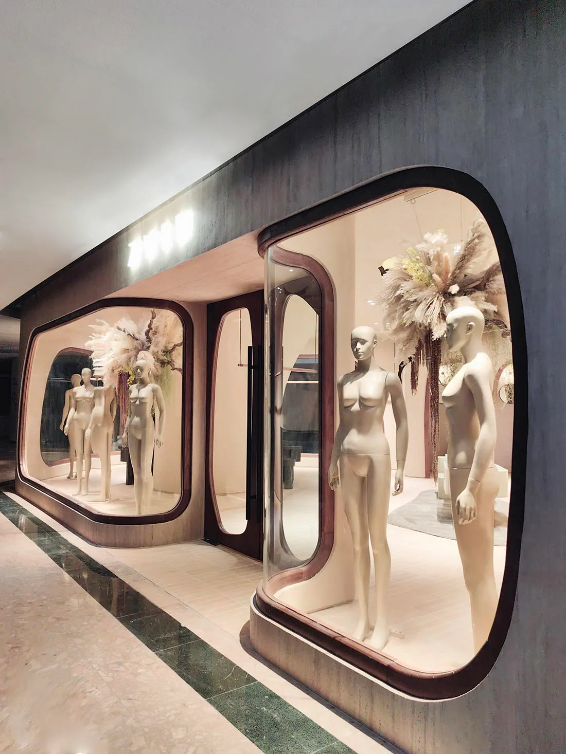 A minimalist fashion retail storefront featuring glass architectural features and decor elements.