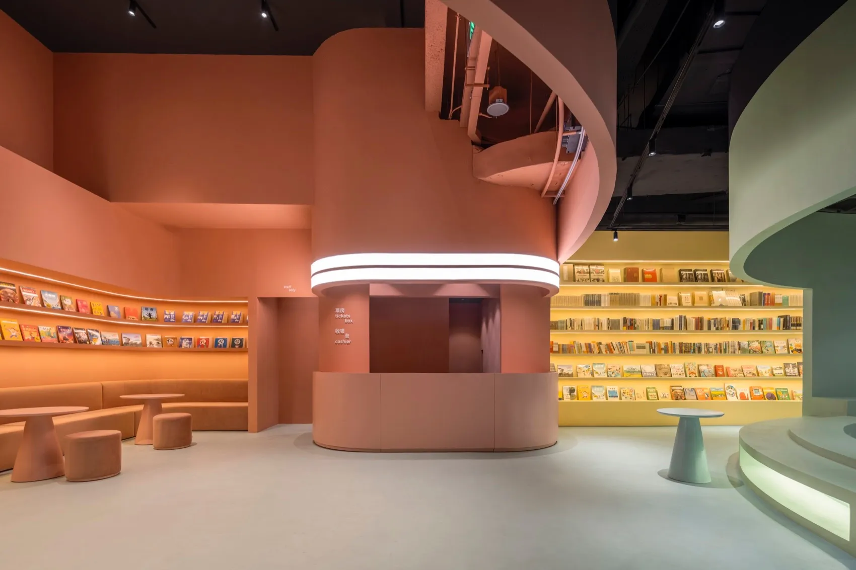Modern bookstore with concrete walls, neon lighting, and shelves filled with books.