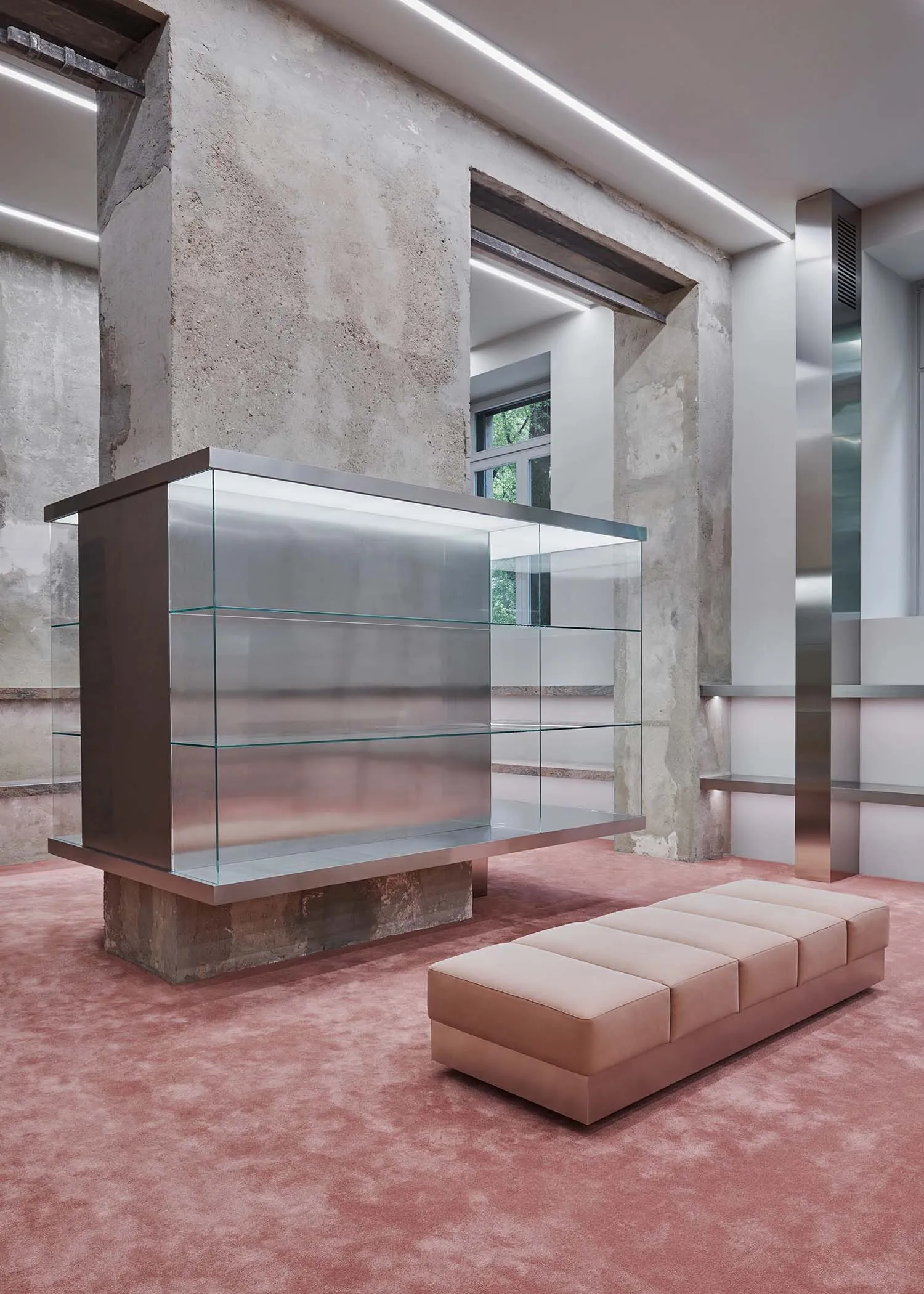 Modern lobby featuring glass showcases, concrete pillars, and metal structural elements.
