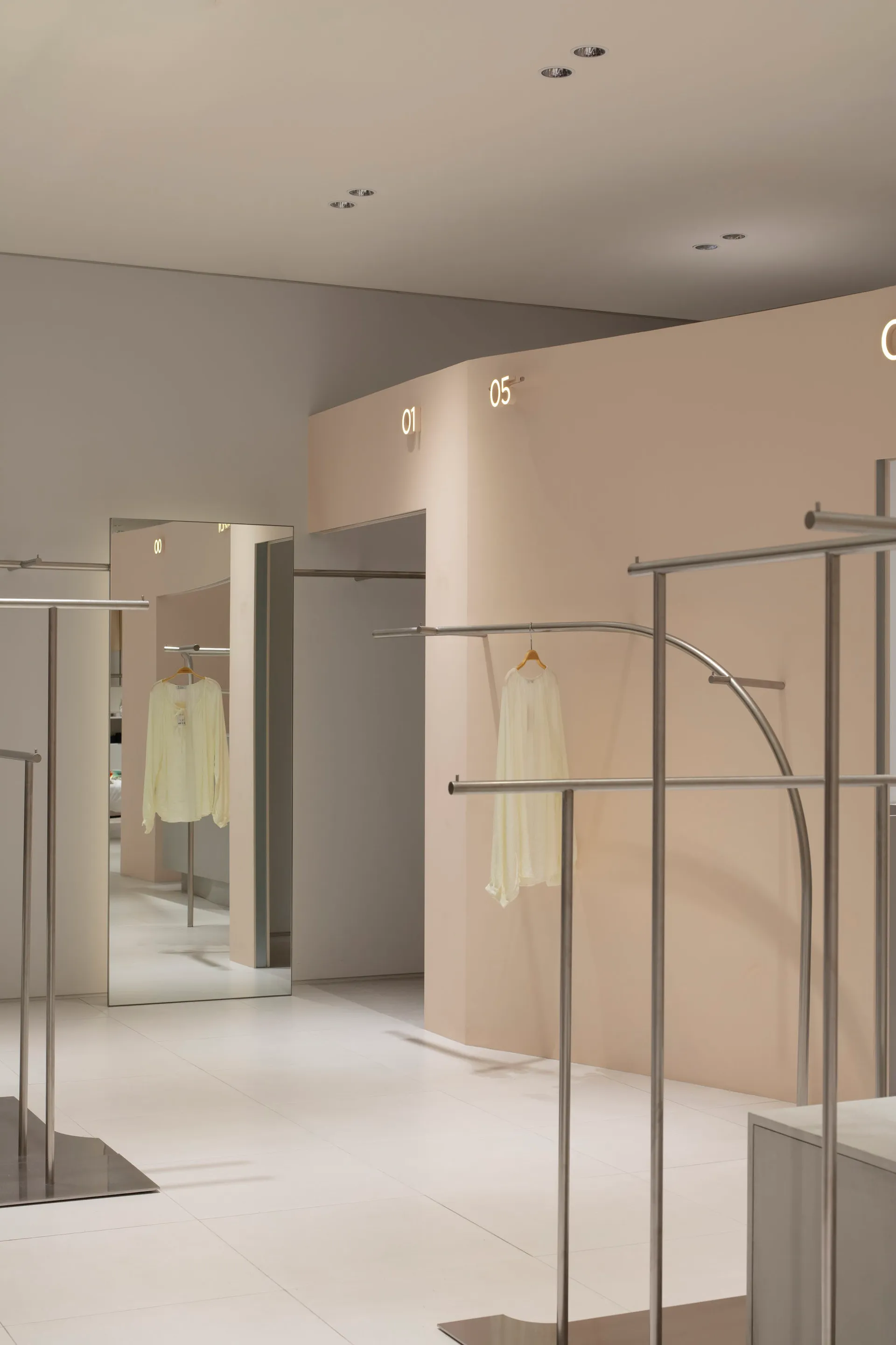 現代零售店室內,展現極簡金屬衣架與米色牆面。