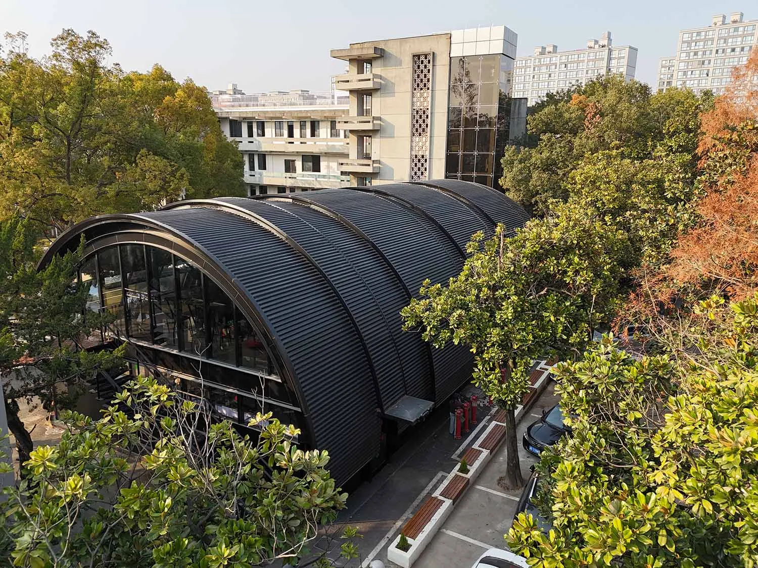 A modern library with a metal-roofed exterior surrounded by greenery.