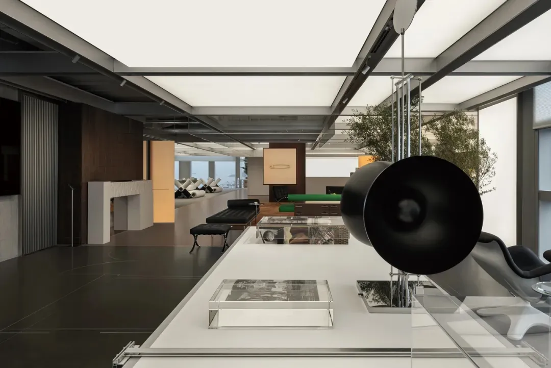 An industrial-style office interior with concrete floors, glass walls, metal elements, and a plant.