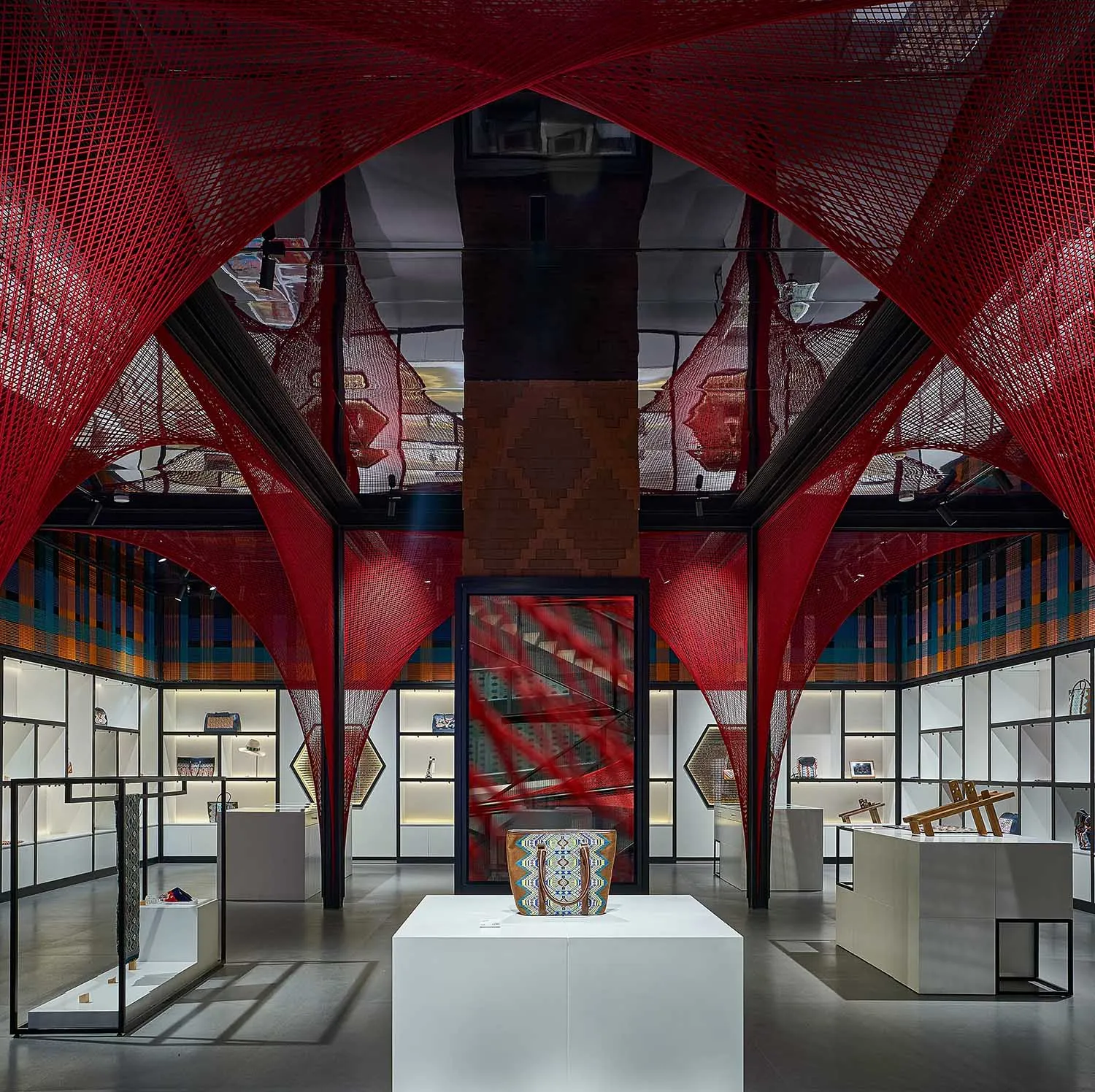 Modern retail space with red netting installation, glass showcases, and glass walls