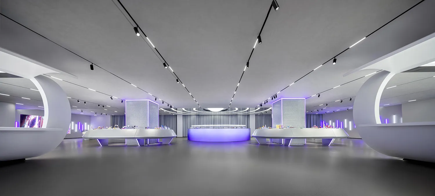 A modern minimalist retail space featuring sleek white surfaces and purple lighting.