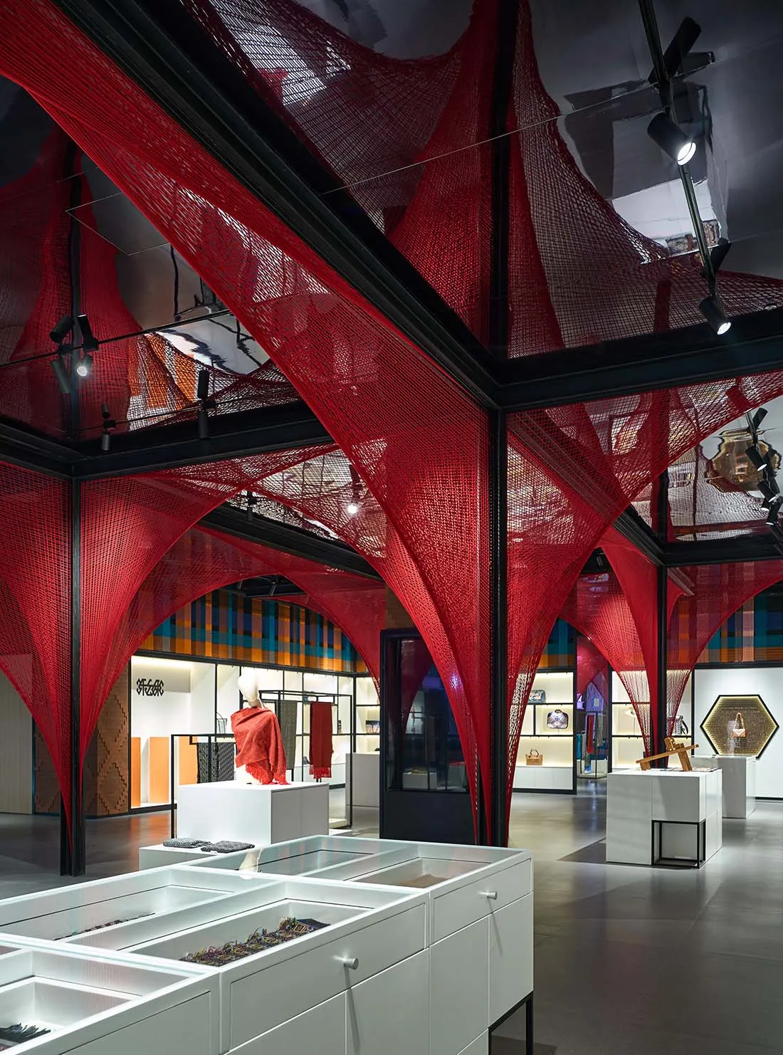 A retail space featuring red tension fabric structures and white display cases.
