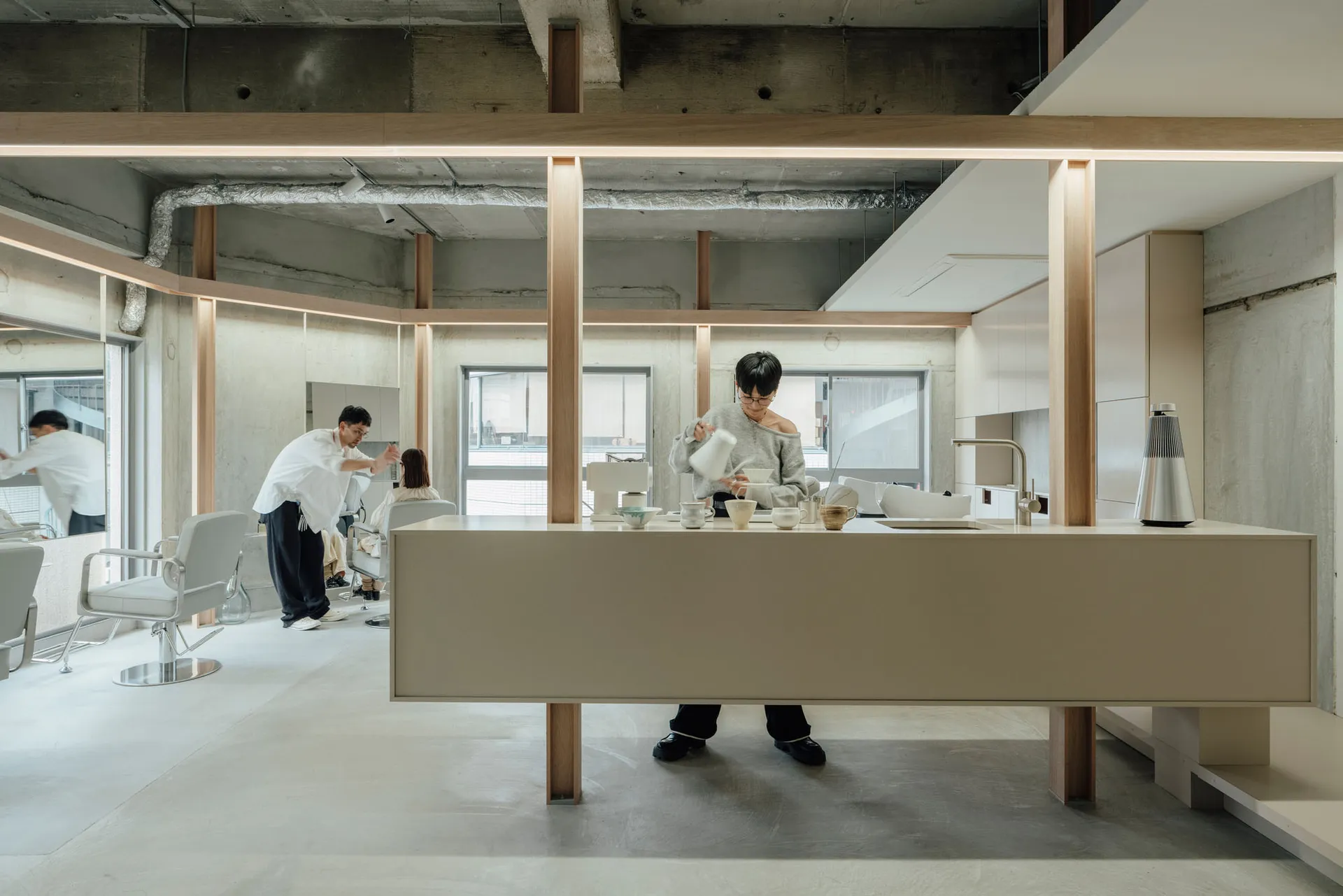 Person pouring coffee in a minimalist coffee shop with concrete kitchen counter