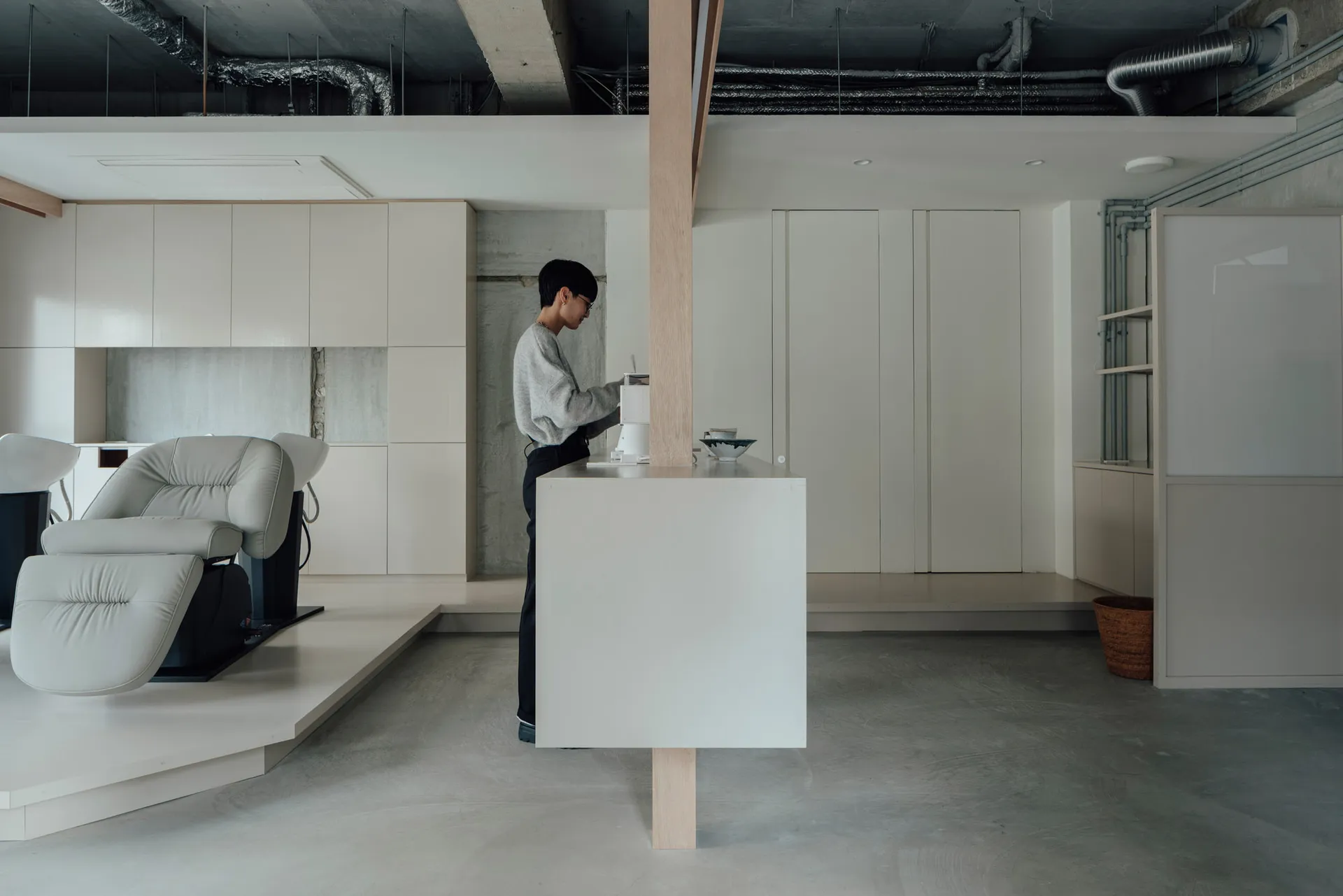 Minimalist living room with concrete floor, white walls, and furniture.