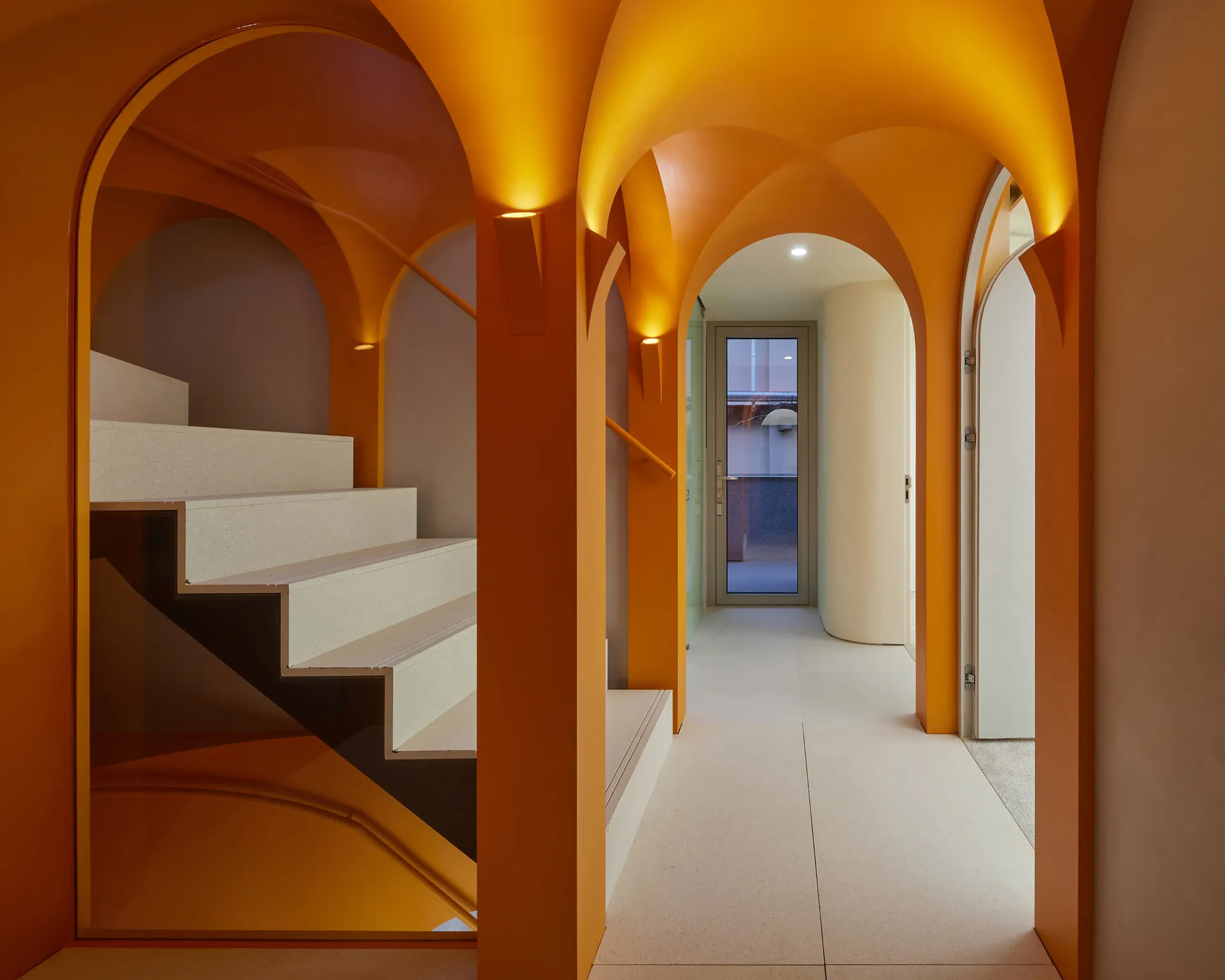 Modern interior design featuring a concrete staircase and corridor with arched ceilings and warm lighting.